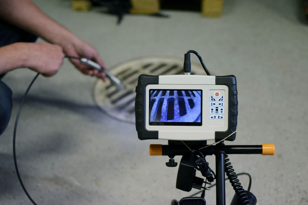 close-up of sewer inspection camera entering a cleanout or drain opening close-up of sewer inspection camera entering a cleanout or drain opening