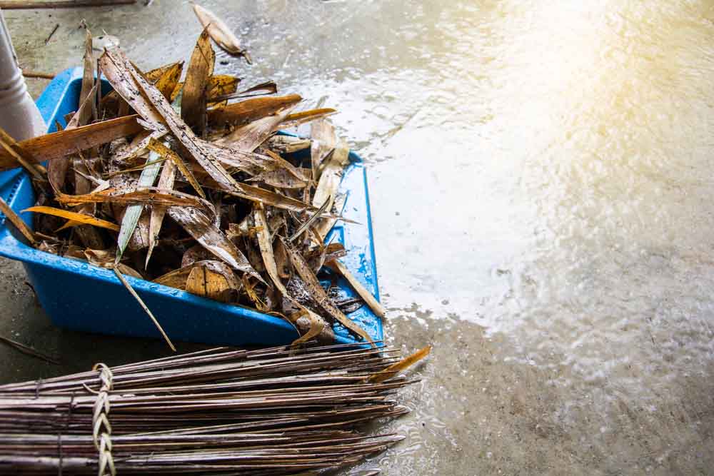 a person clearing fallen leaves out of their storm drains